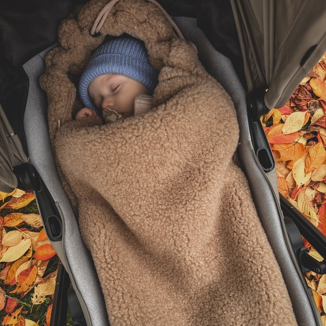 Baby schläft im Kinderwagen in einem braunen Wollfußsack aus Schurwolle